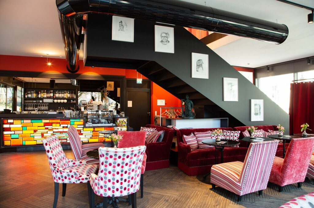 Stilvolles Mutter Ey Café nahe dem Hotel The Wellem Düsseldorf mit farbenfroher Bar, gemütlichen Samtsofas und kunstvoller Atmosphäre.