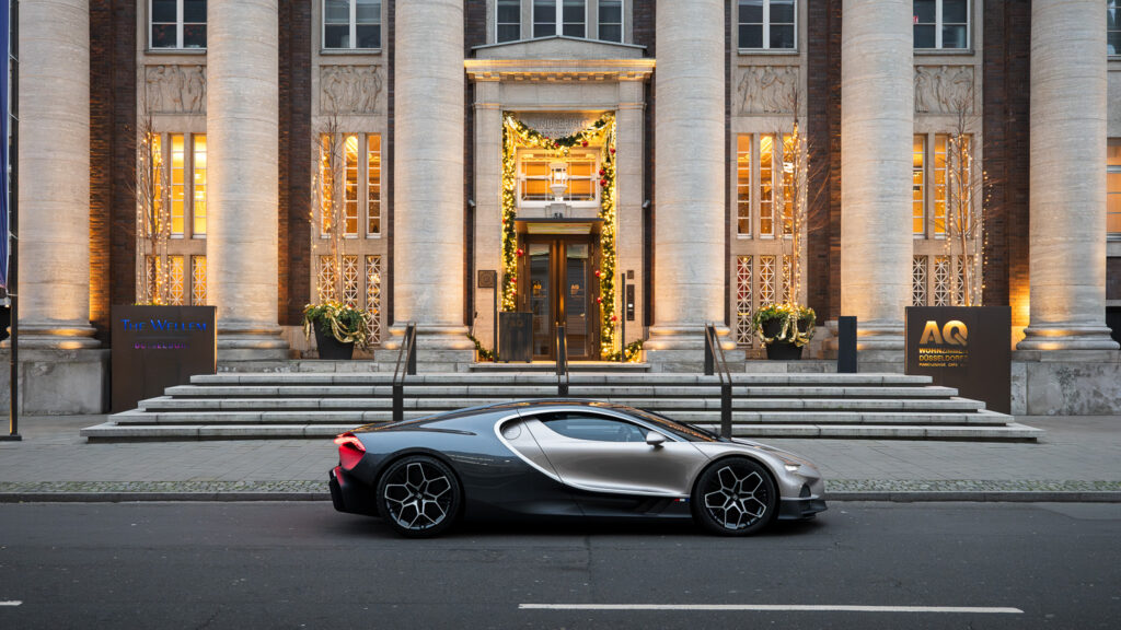 Luxurious exterior view of The Wellem Hotel in Düsseldorf with festive Christmas lights and an elegant super sports car in front of the historic pillared entrance.