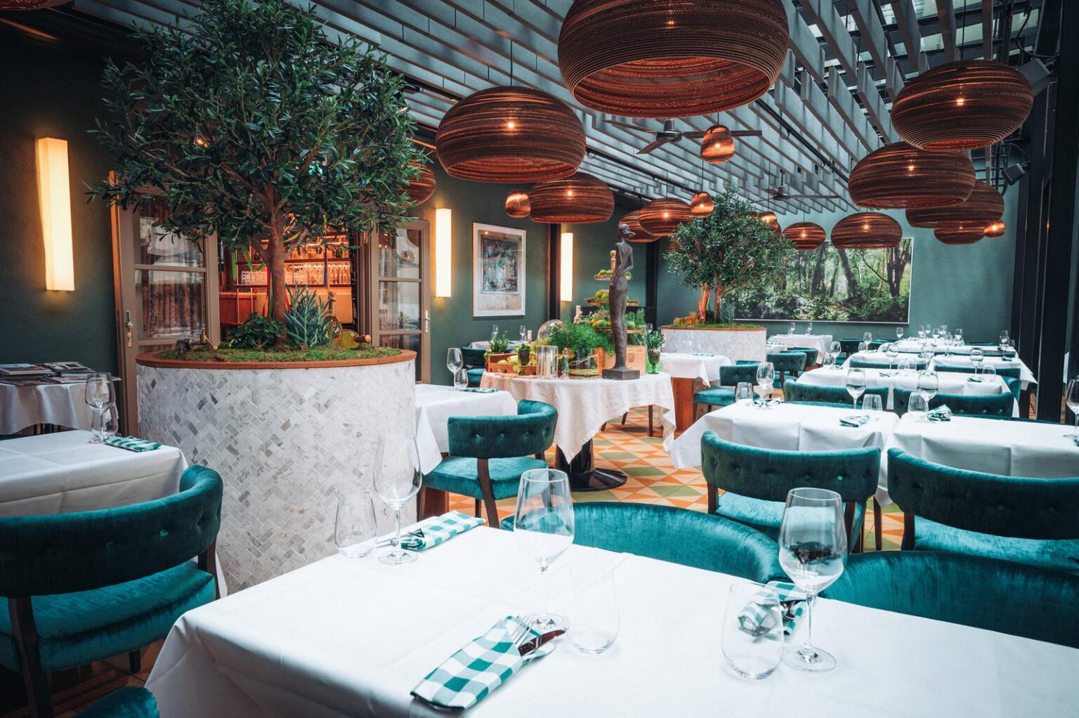 Stilvoll gedeckter Innenraum des Restaurants Pitti – Cucina Italiana im Hotel The Wellem Düsseldorf mit großen Olivenbäumen und warmen Designerleuchten