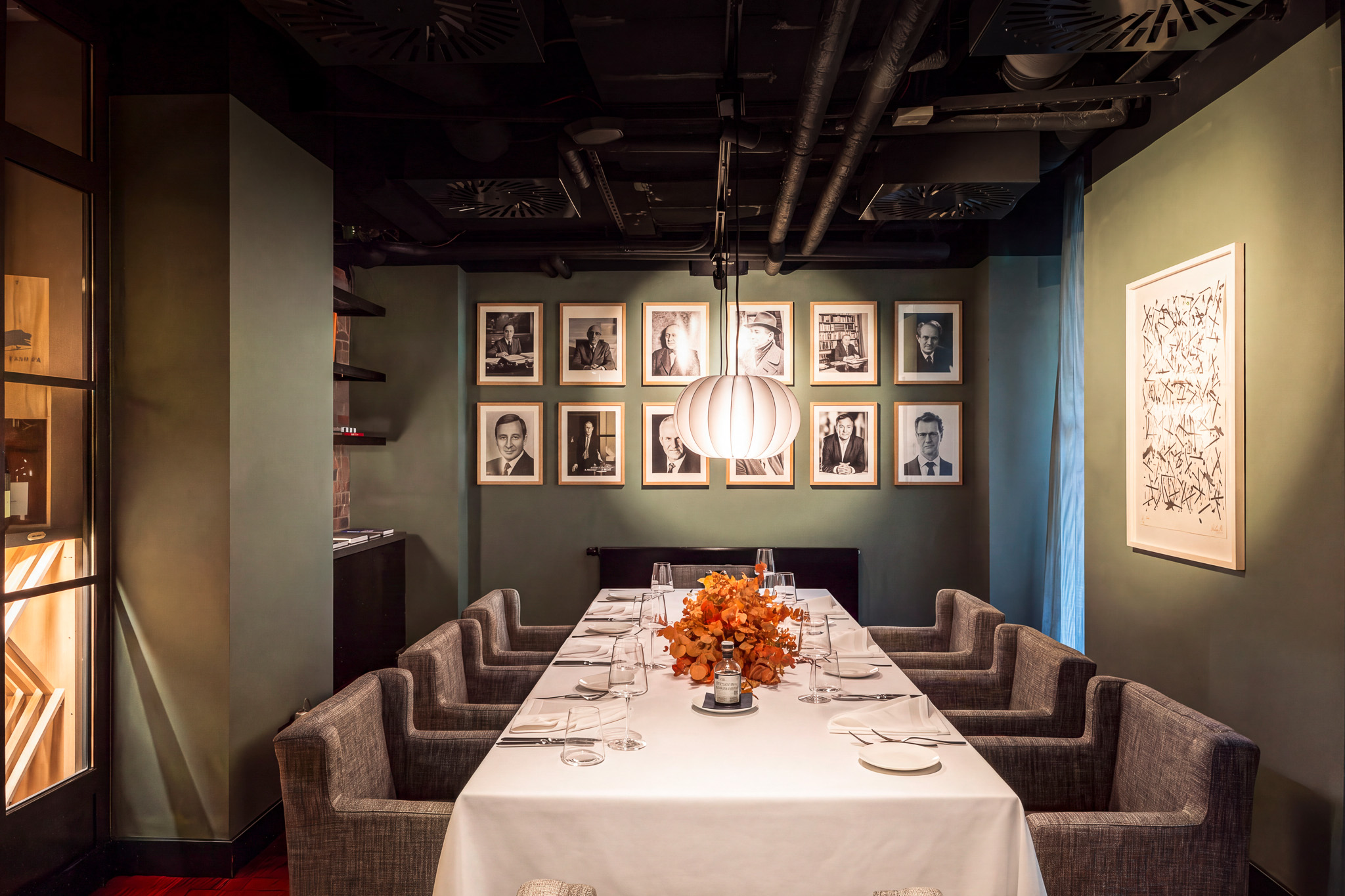 Private-Dining-Bereich im il punto mit gedeckter Tafel und Porträts an der Wand
